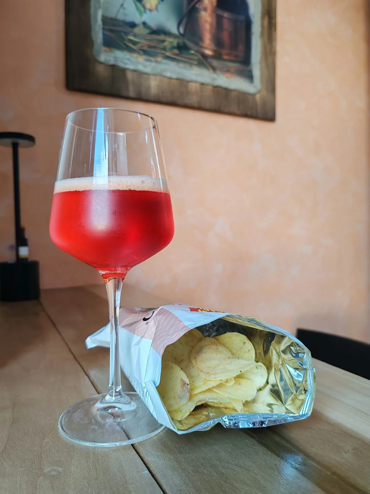 Un calice di aperitivo rosso con patatine sul tavolo di Vini Le Botti