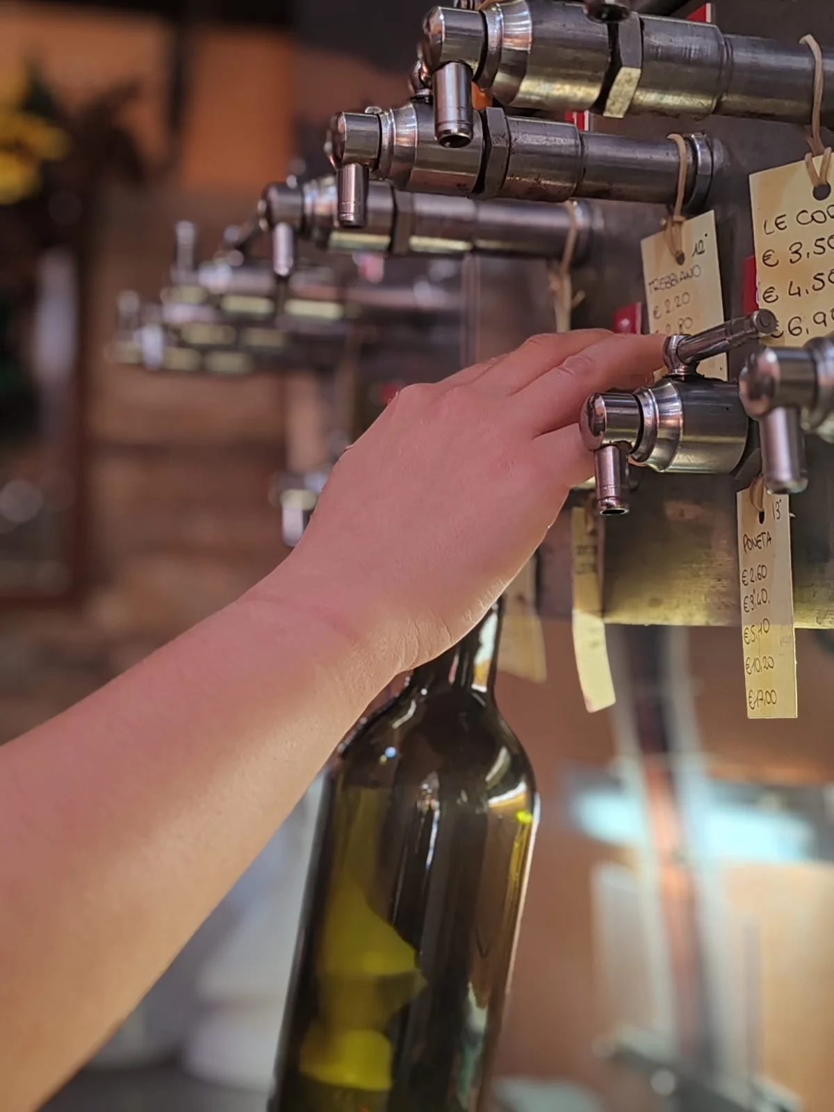 Il vino viene versato dalla spina in una bottiglia, nell’enoteca Vini Le Botti
